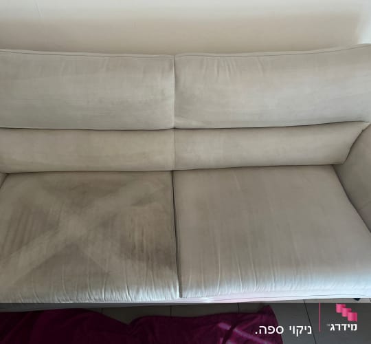 ספה עם כתמים כהים על המושב, מגבת ורודה על הרצפה